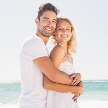 Smiling young couple hugging on the beach