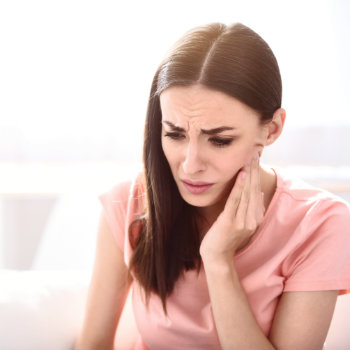 brunette holding her cheek with toothache