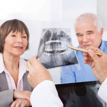 dentist explaining dental x-ray to senior couple in clinic