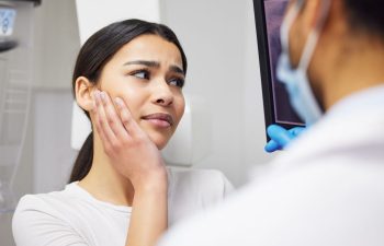 An emergency dentist explaining showing a digital dental image and treatment options to a woman with dental pain
