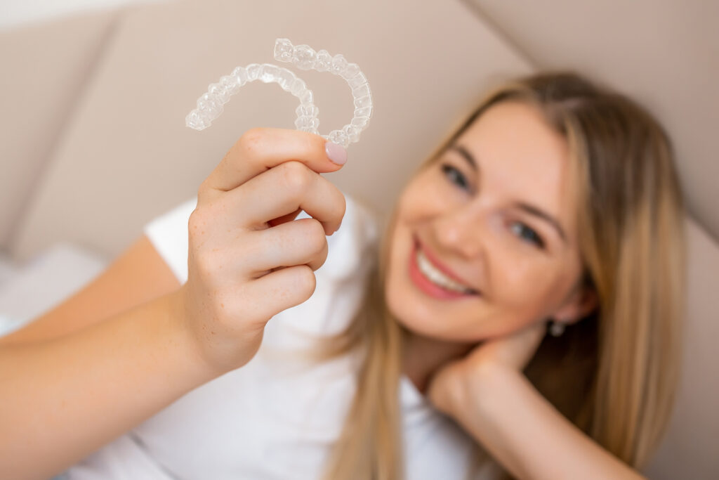Why Are People Choosing Dental Implants Over Dentures? 11 Woman holding a clear dental aligner
