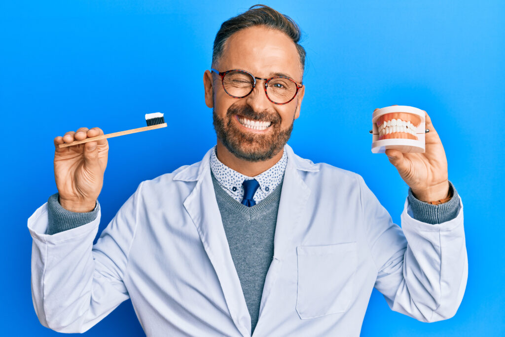 Dental Implants 101: A Permanent, Natural-Looking Tooth Replacement Option 6 Dentist holding toothbrush and jaw model
