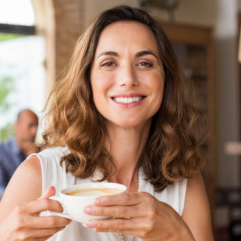 Mature woman smiling holding cup Duluth Dental Studio care